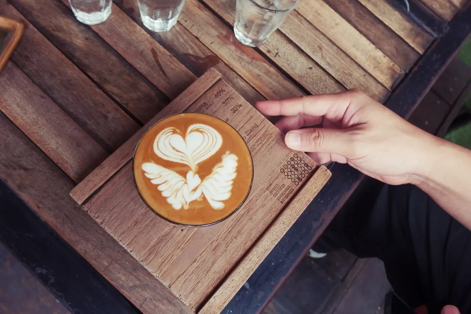 A latte with a heart and wings poured in the foam, on a wooden tray at a Chiang Mai cafe