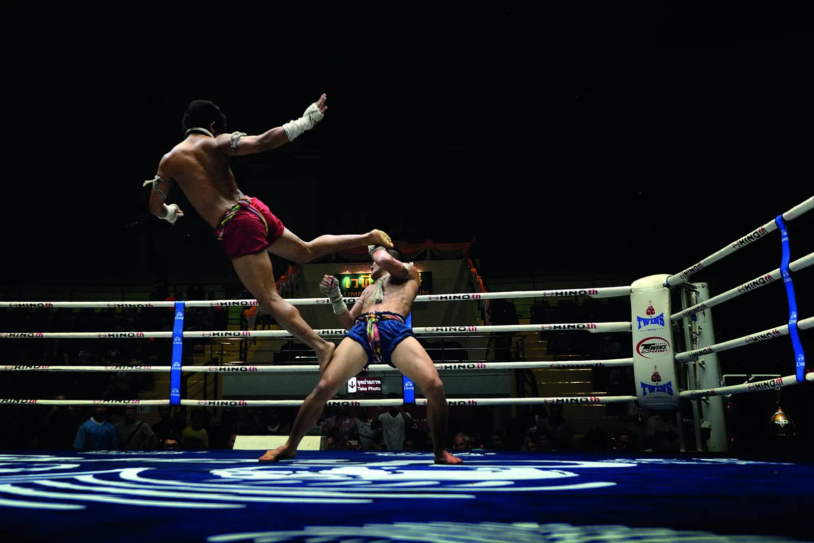 A Muay Thai fighter flies in with a knee under the lights at Lumpinee Boxing Stadium