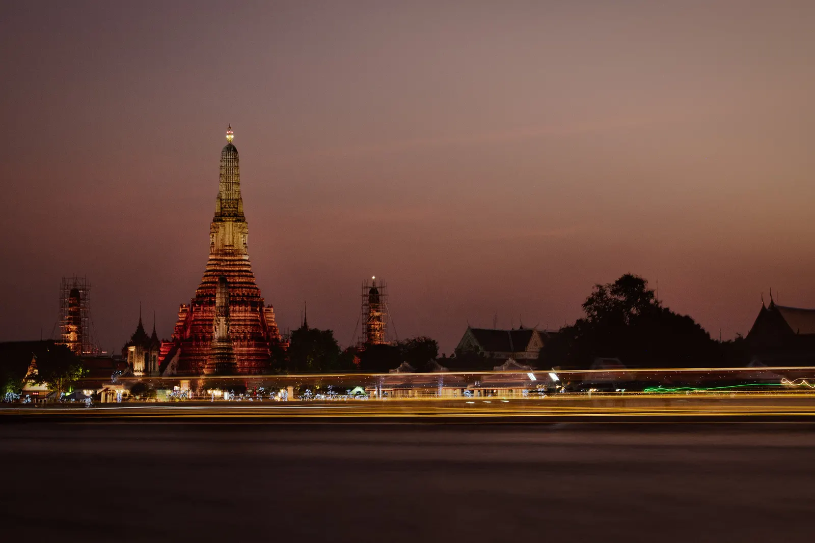 Wat Arun lit up across the Chao Phraya River at dusk