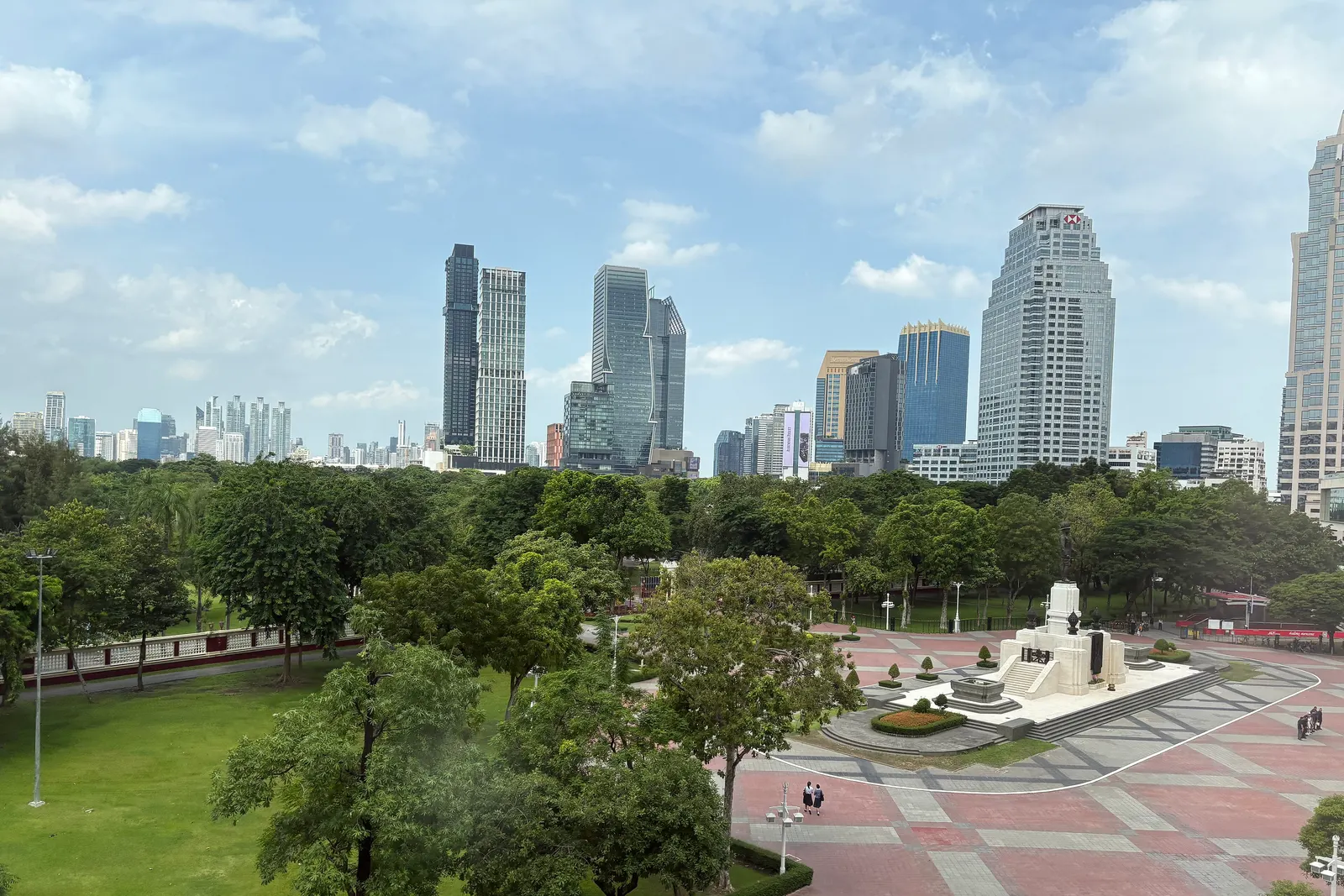 Lumphini Park's lawns and trees with the Silom towers behind, seen from the BTS
