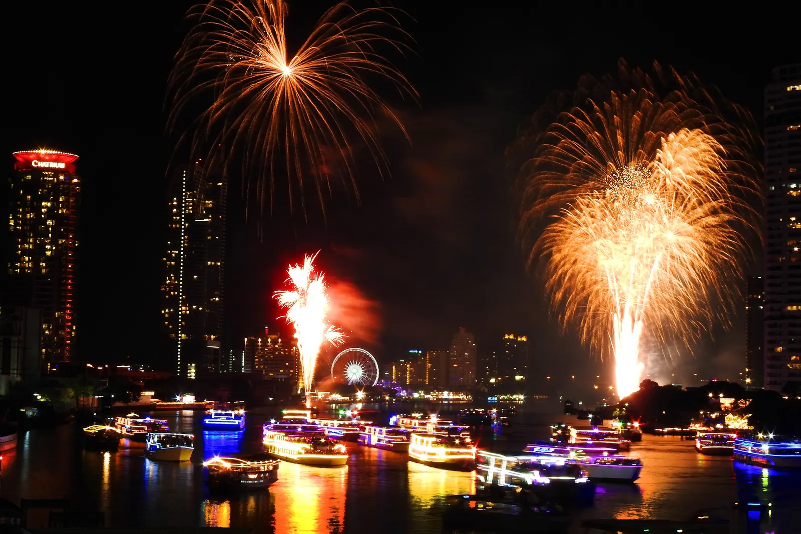 New Year fireworks over the Chao Phraya River just after midnight, with lit-up dinner boats on the water