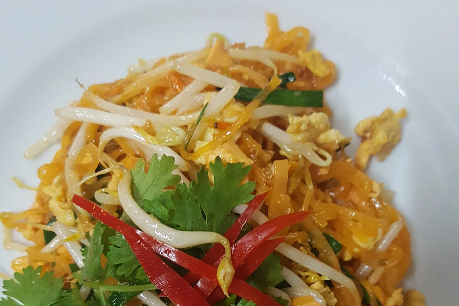 Thipsamai pad thai close up: orange sen chan noodles with egg, bean sprouts, chives, coriander and strips of red chilli