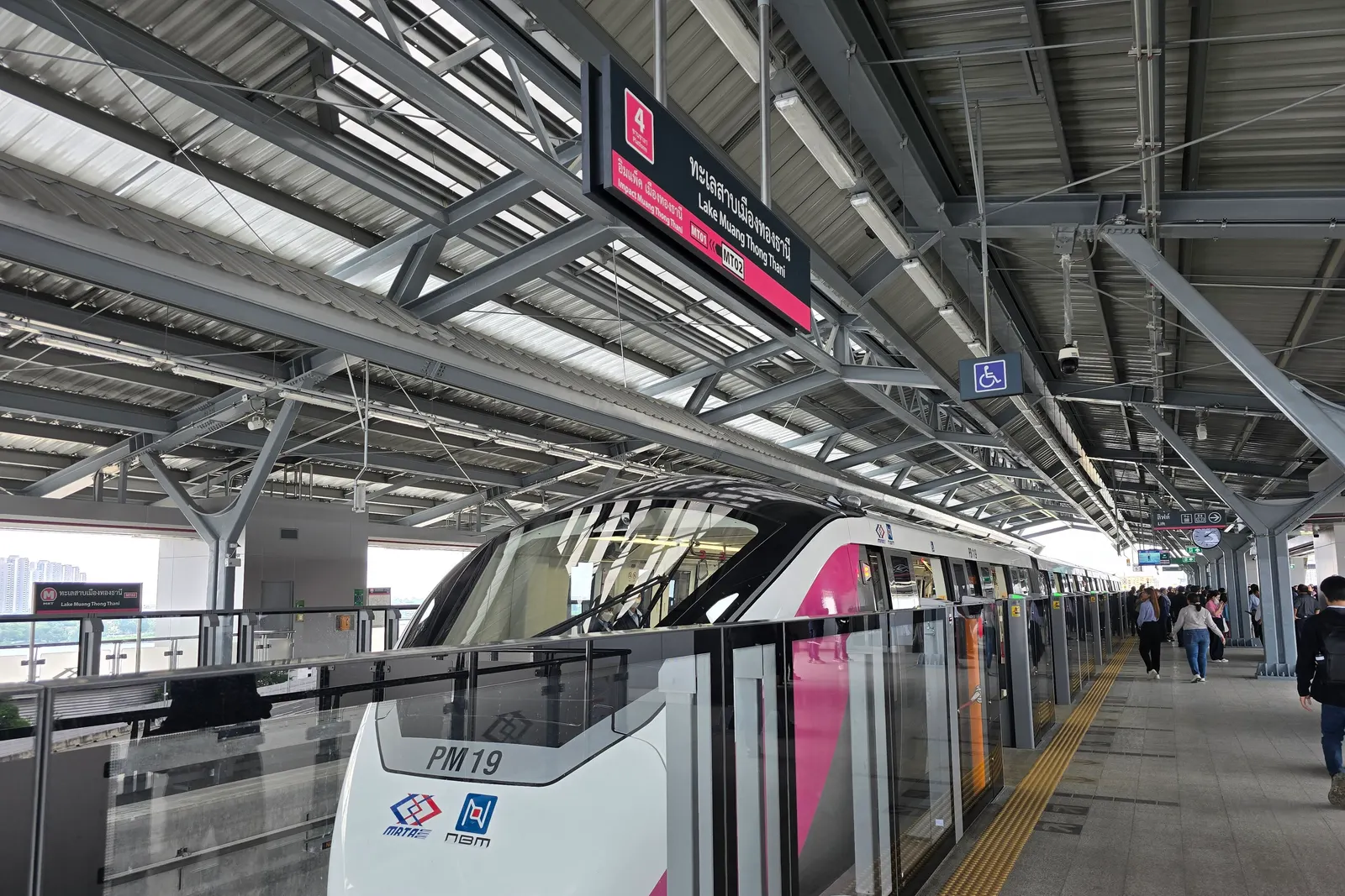 A pink and white monorail train waiting at the Lake Muang Thong Thani platform