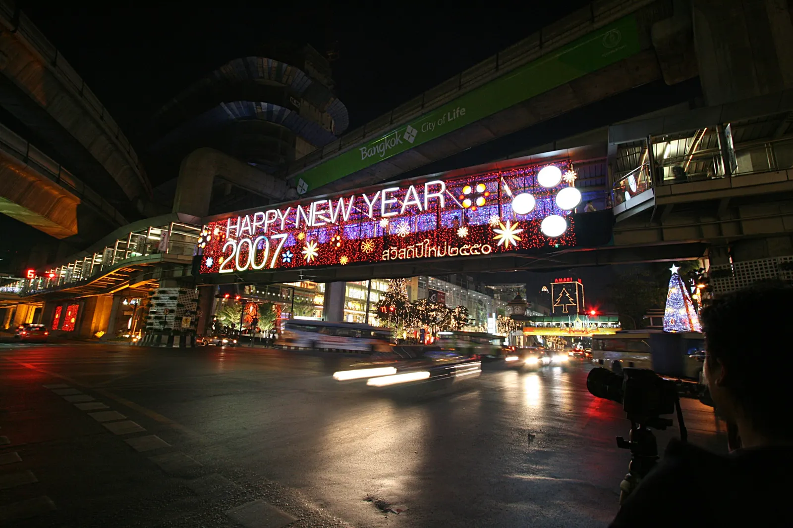 拉差巴颂路口的天桥上挂着"Happy New Year 2007"的灯牌，旁边是中央世界，桥下车来车往