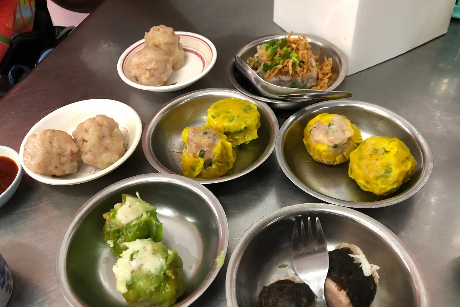 Siu mai and other dim sum on small metal plates, a Phuket breakfast