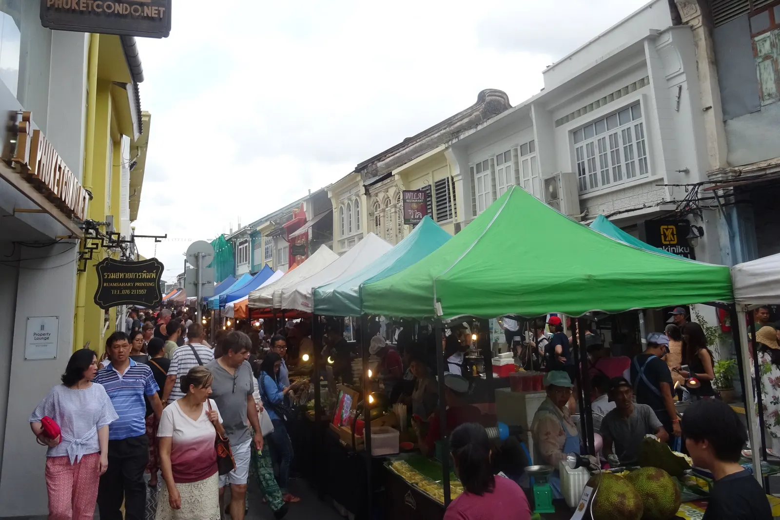 Stalls under green and white tents and a Sunday crowd on Thalang Road, Phuket Old Town