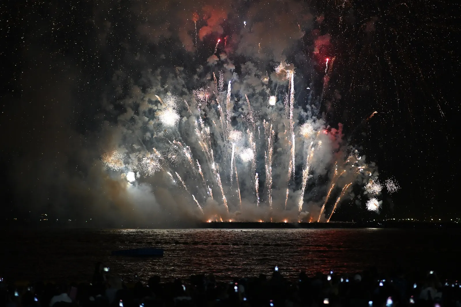 Fireworks over the bay at the Pattaya International Fireworks Festival on 28 November 2025, with the crowd on the beach holding up their phones