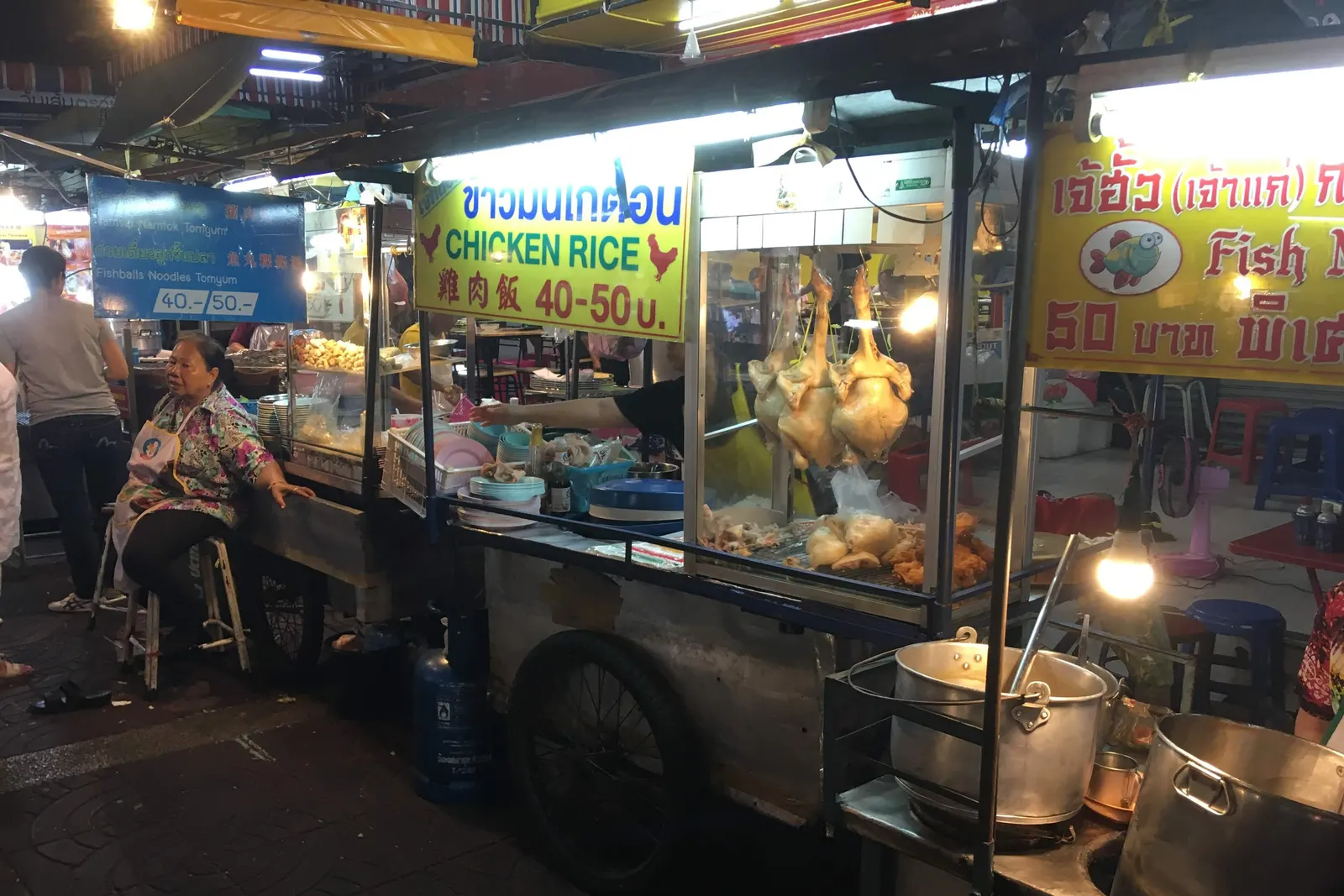 Chicken rice and fish ball noodle carts lit up at night in Bangkok's Chinatown