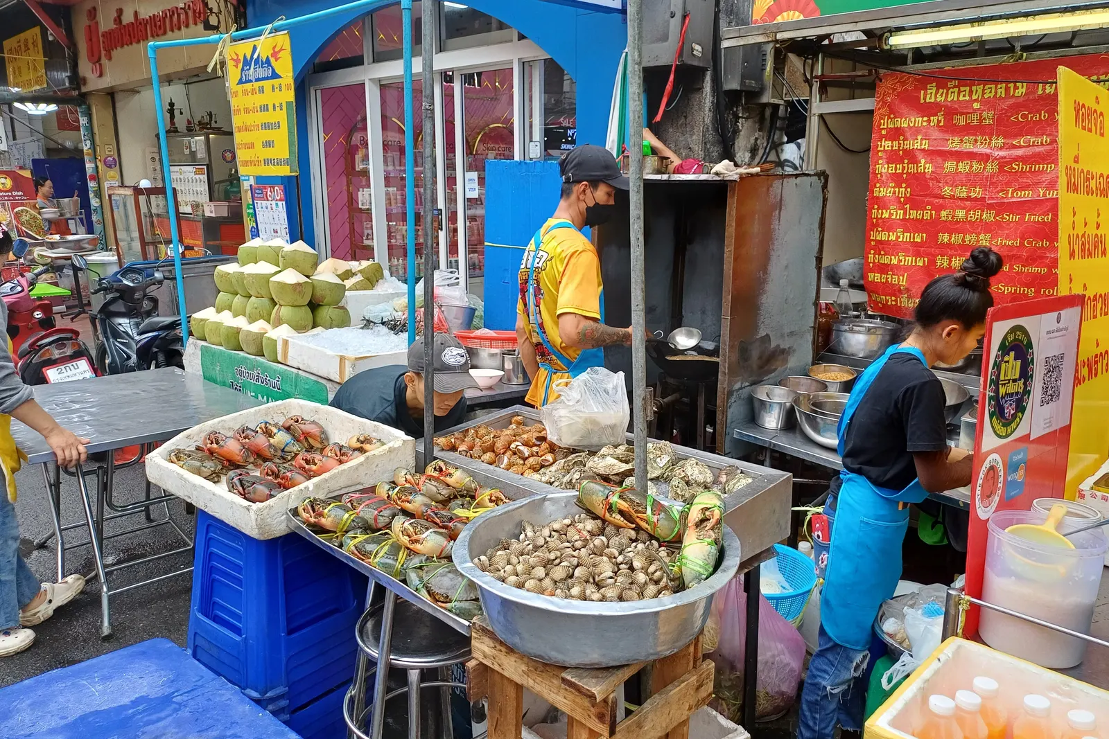 Crabs, clams and coconuts laid out at a seafood stall in Bangkok's Chinatown, with the wok burning behind